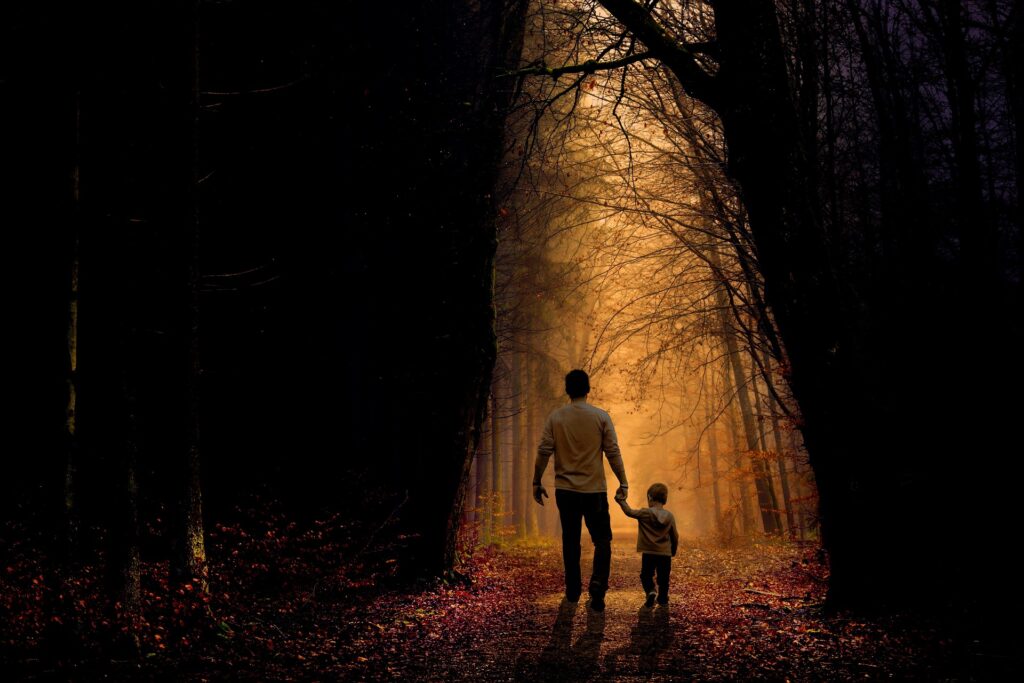 When Anger Hits Home: Christian father walking hand in hand with his son through a forest path toward warm light, symbolizing grace, patience, and faith in fatherhood.